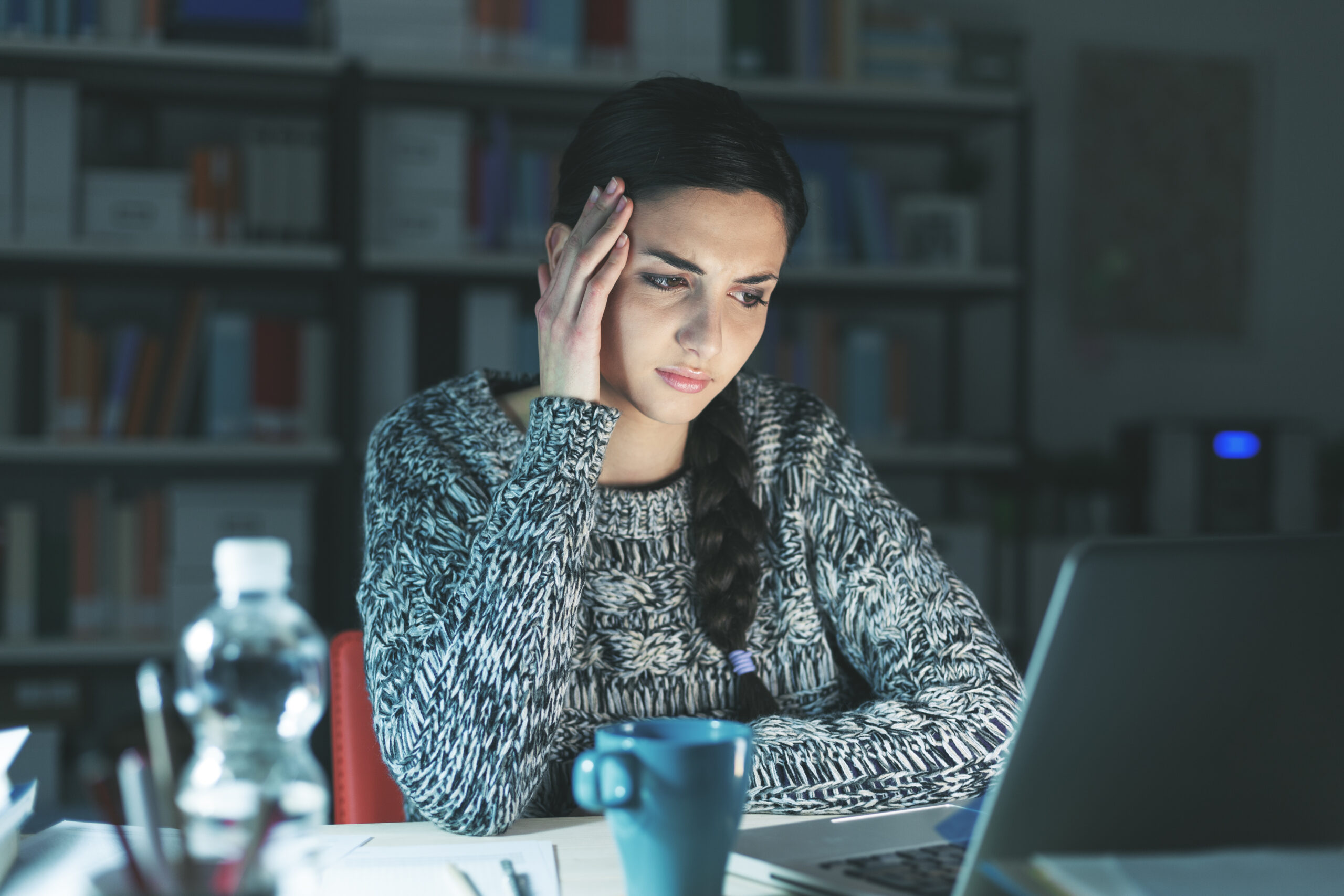 attractive woman with serious expression working on the laptop at night