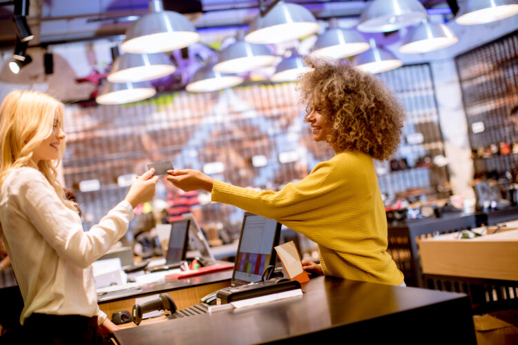 Happy female customer paying with credit card in fashion showroom