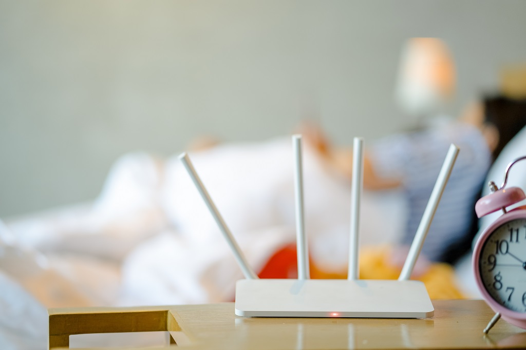 Wireless router and a young man using a smartphone in bedroom.