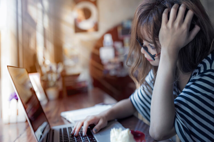 frustrated woman working on laptop in cafe