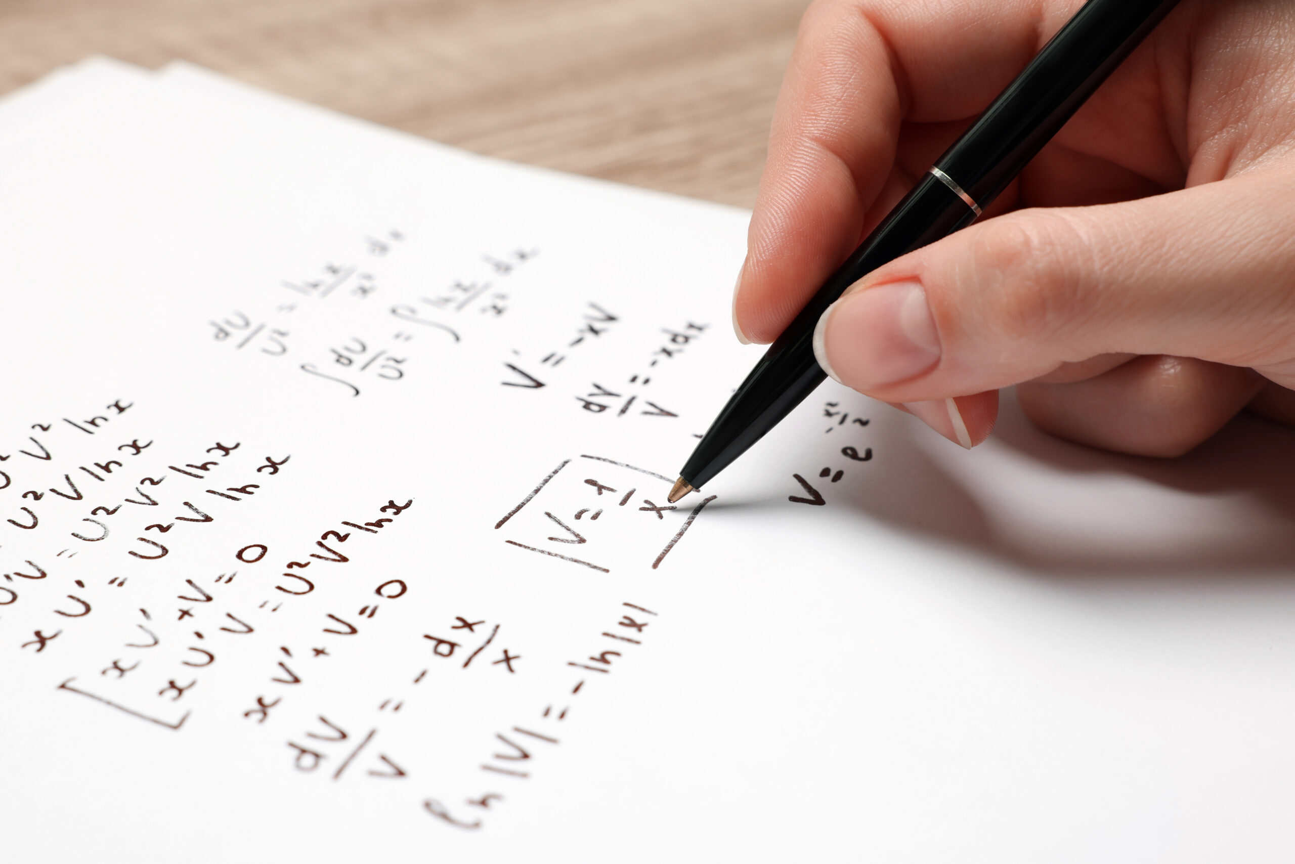 female hand solving mathematical problems on paper
