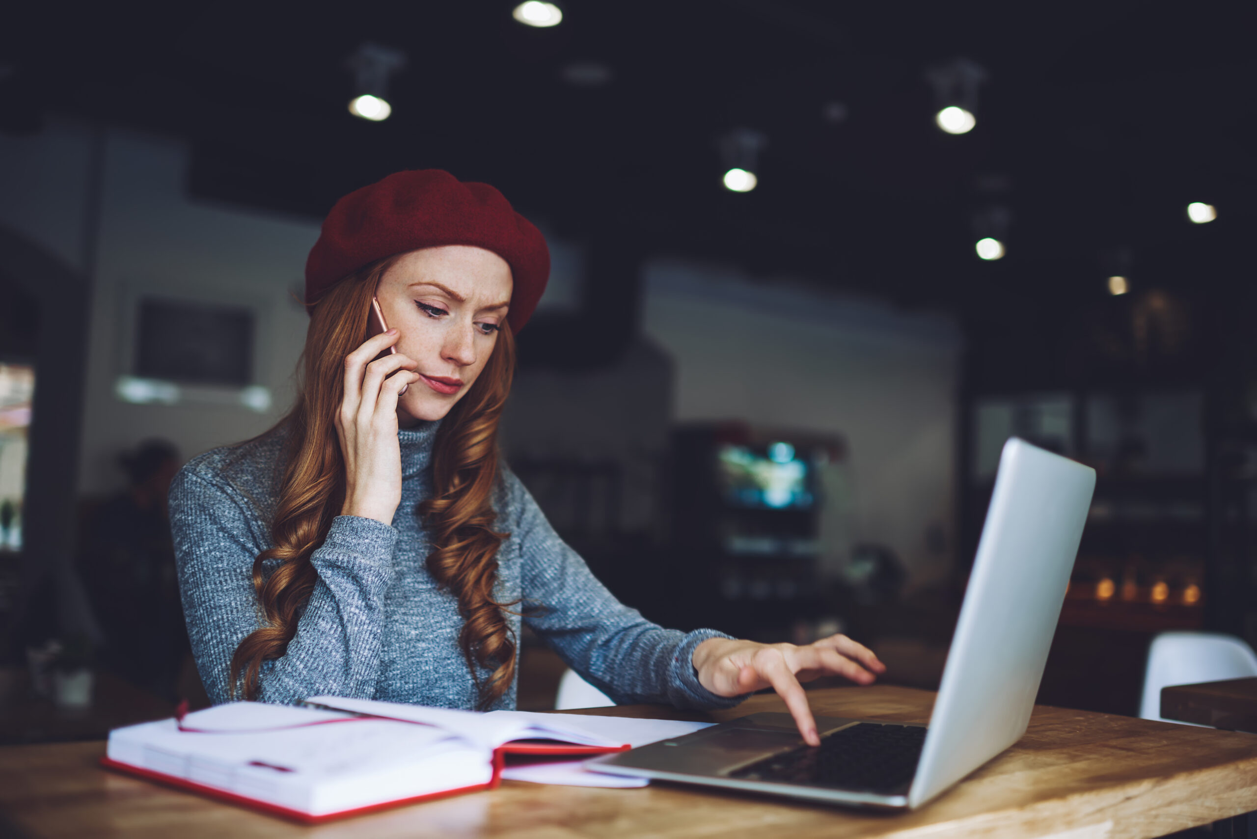 frowning woman using laptop while making a phone call