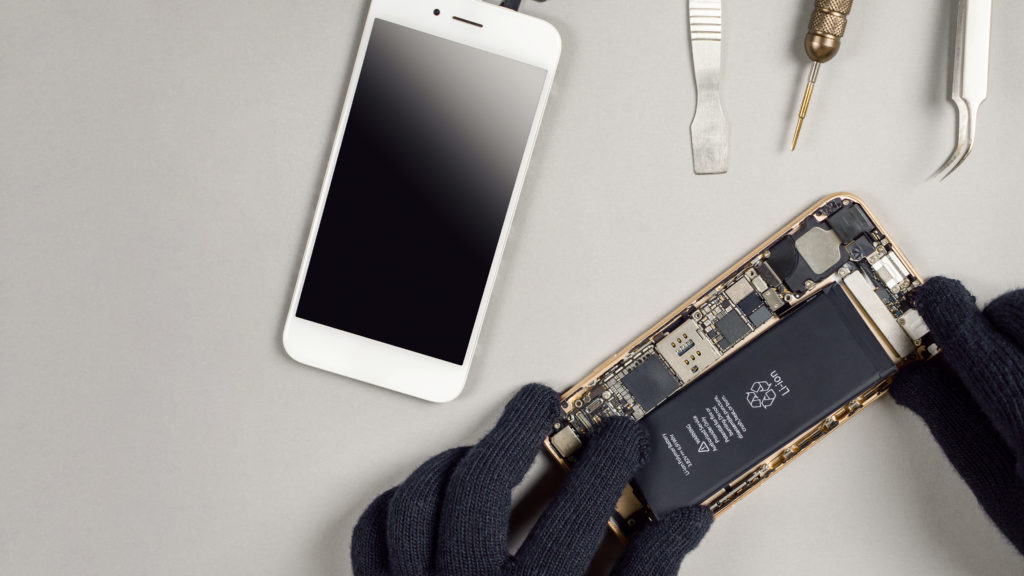 Technician repairing broken smartphone on desk 