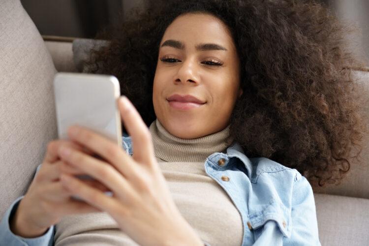 relaxed woman laying on couch texting using her phone