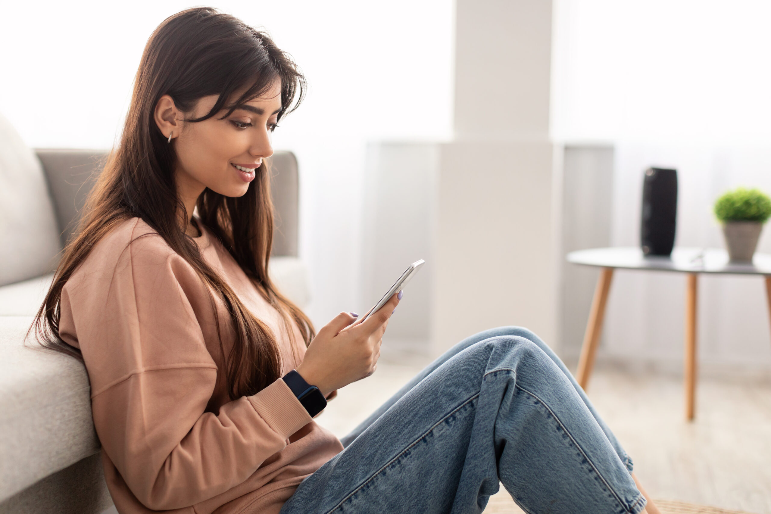 smiling woman reading a message on smartphone at home
