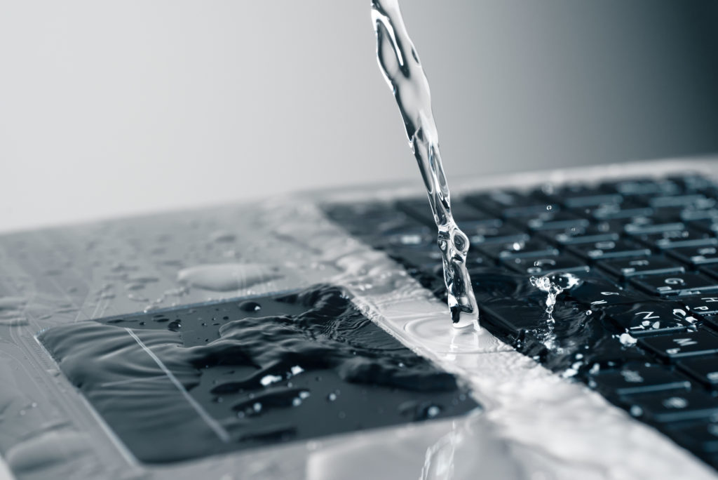 A stream of water pours on the laptop keyboard.