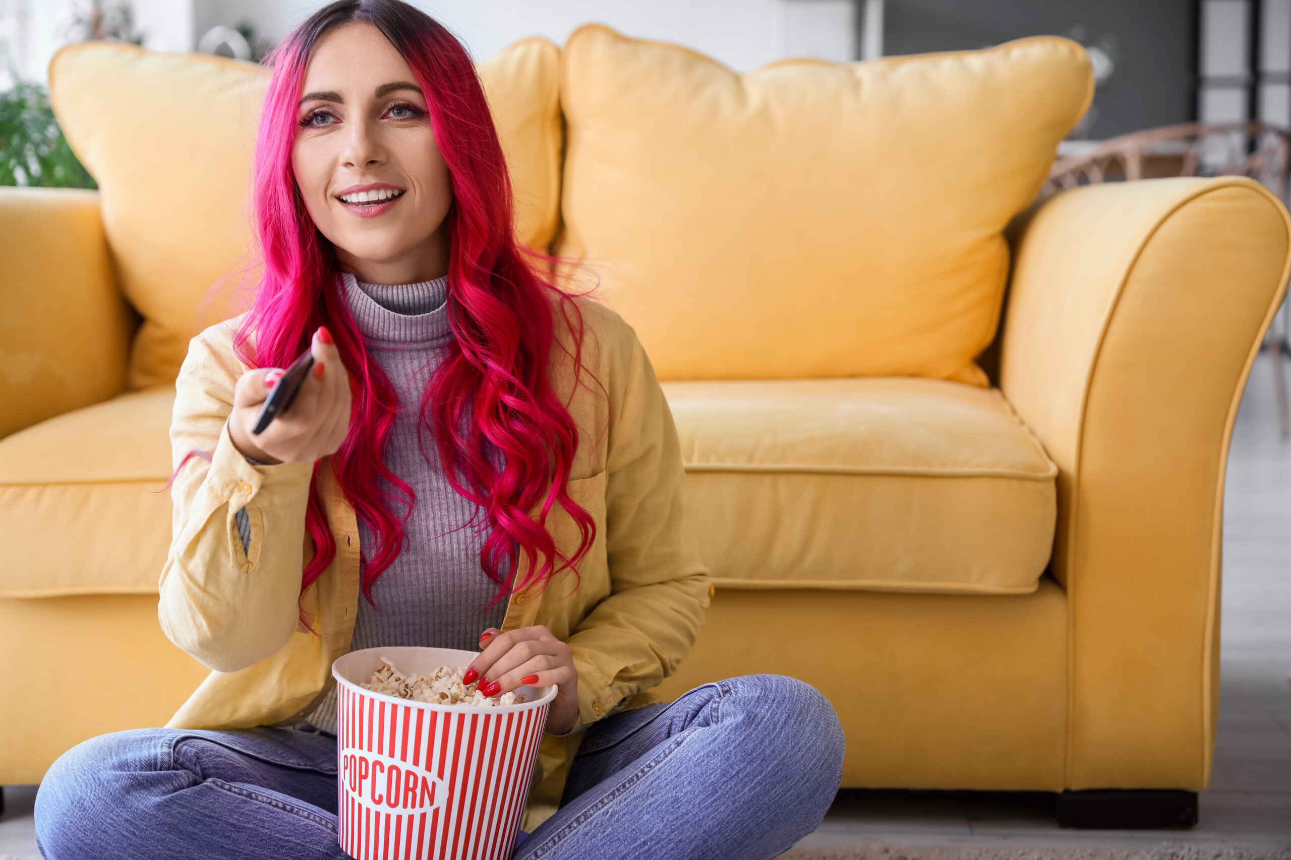 Beautiful woman with popcorn watching TV at home