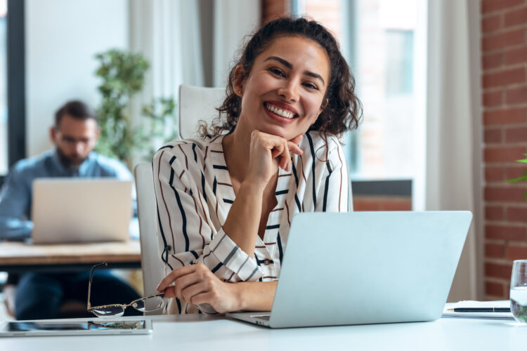 Wanita bisnis yang tersenyum bekerja dengan laptop