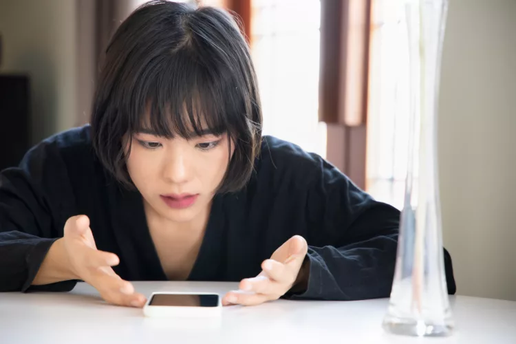 Frustrated Asian woman waiting on her smartphone
