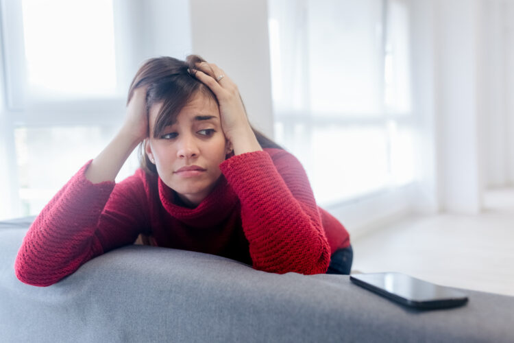 Sad woman looking the phone at home