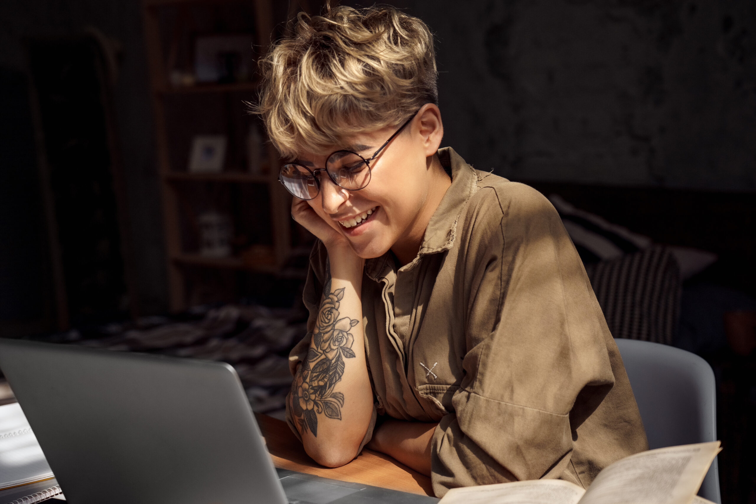 Young woman with short hair and glasses working on laptop