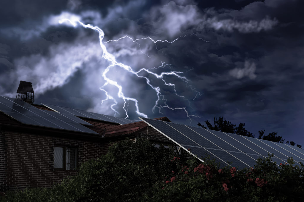 Dark cloudy sky with lightning over house.