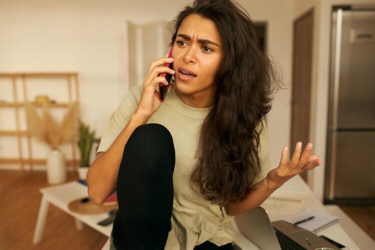 Irate woman arguing with someone over the phone at home
