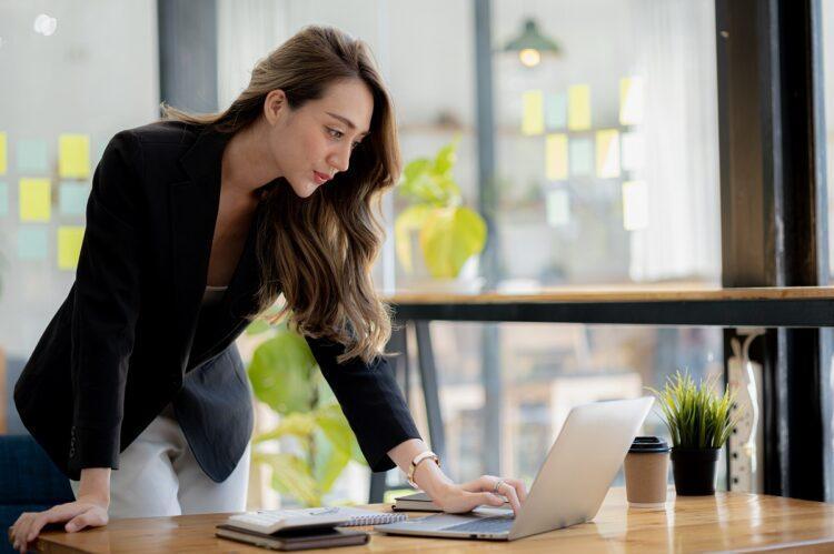 Beautiful woman checking her laptop while standing at office desk
