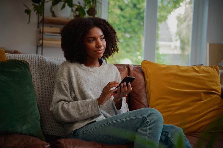 Woman thinking while holding smartphone.