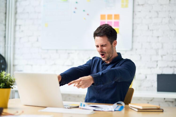 young man celebrate success at work pointing on his laptop