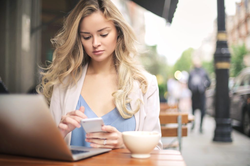 Woman in blue shirt working with her laptop at a cafe.