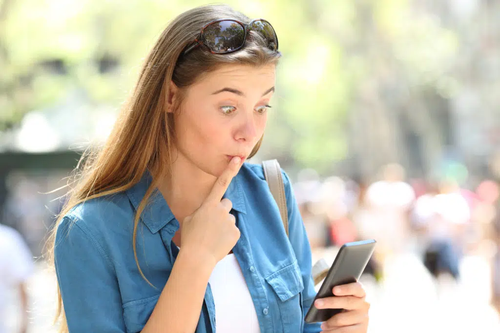 Woman with a shocked expression, making a mistake on her phone.