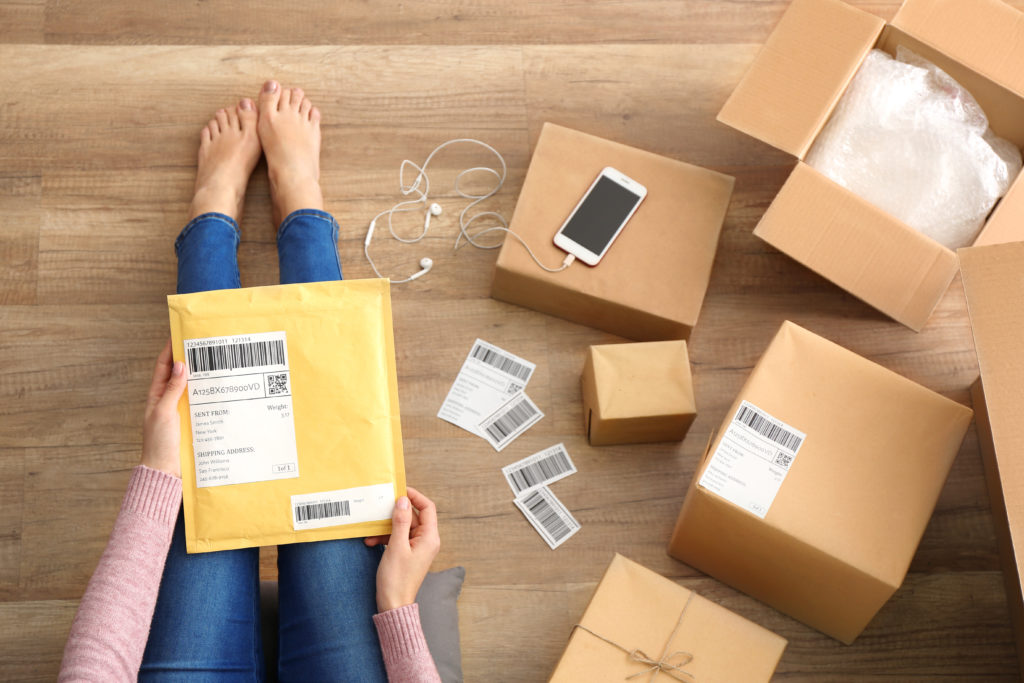 Woman with padded envelopes and parcel on the floor.