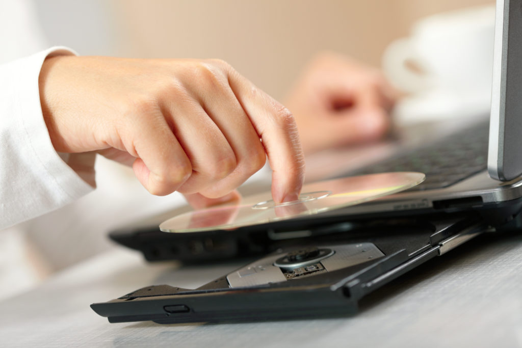 Woman putting CD on laptop player.