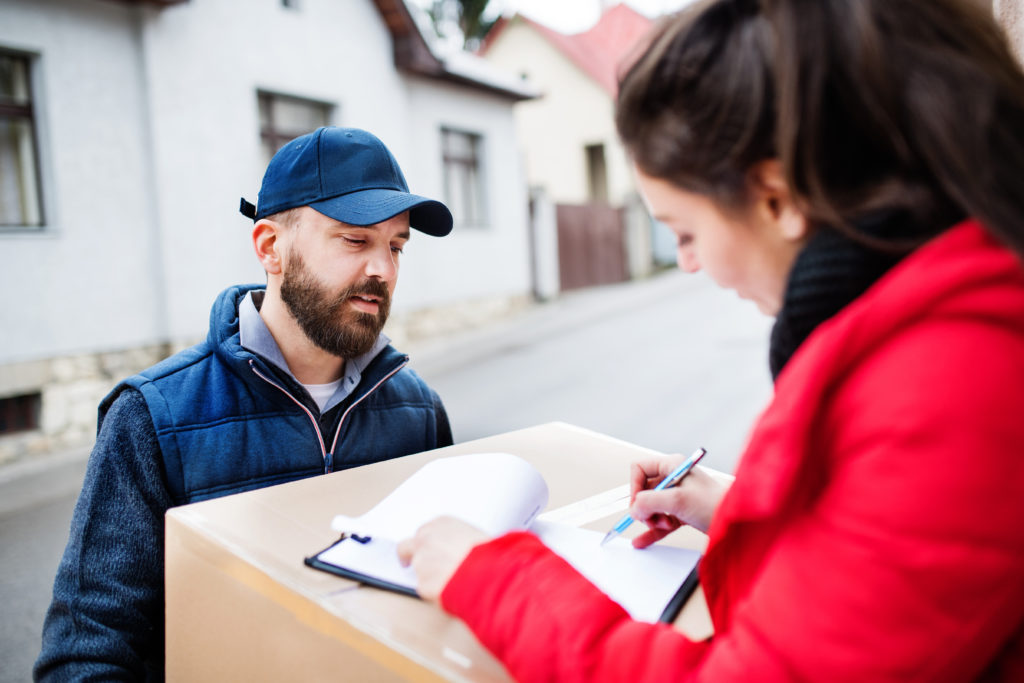 Woman receiving parcel and signing the paper.