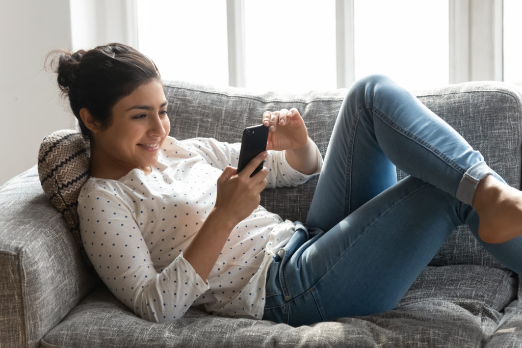 Woman relaxing on couch while using her phone.