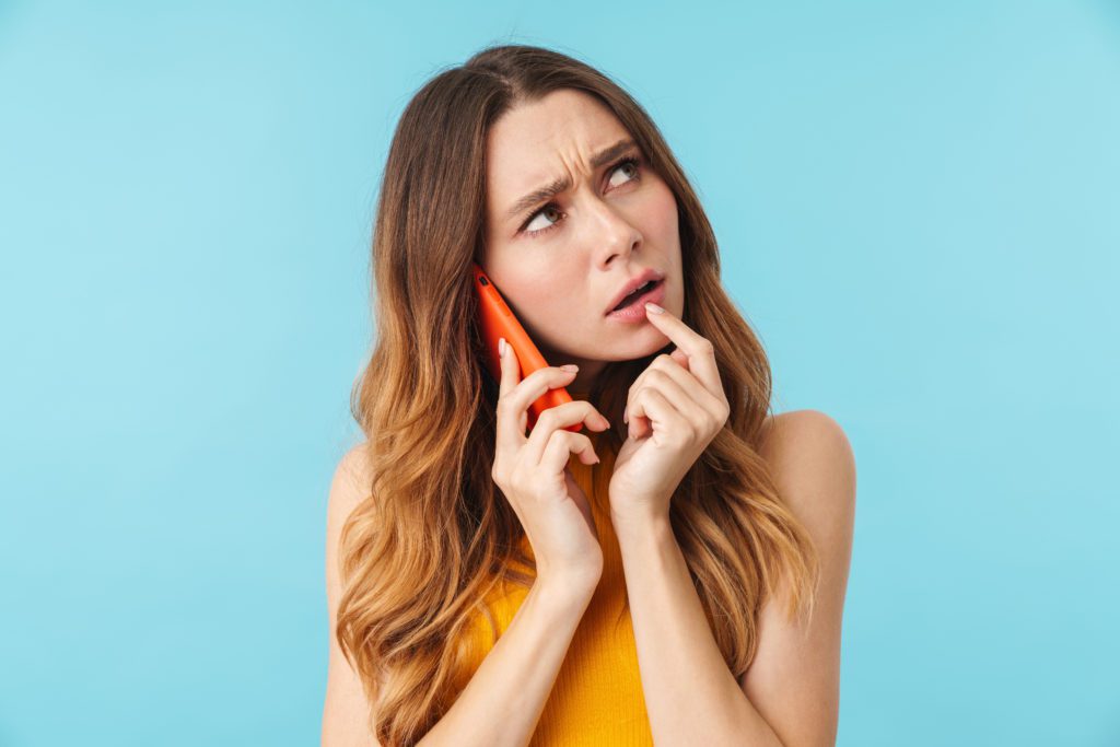 Stressed woman thinking while talking on her cellphone.