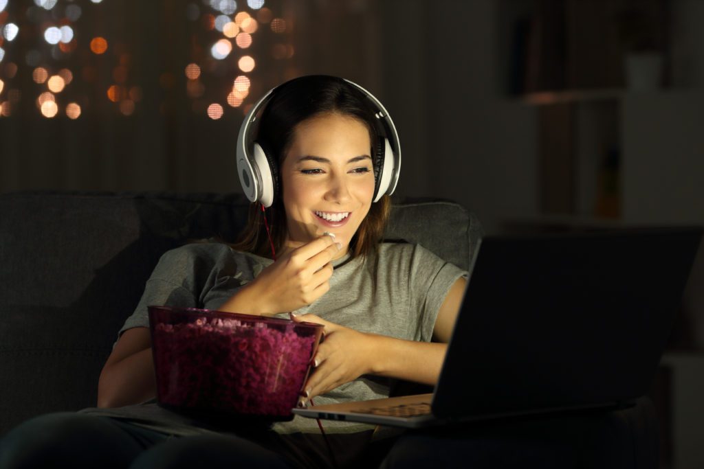 Woman watching shows on her laptop at night.