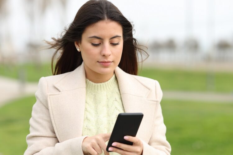 Woman walking using smart phone in a park