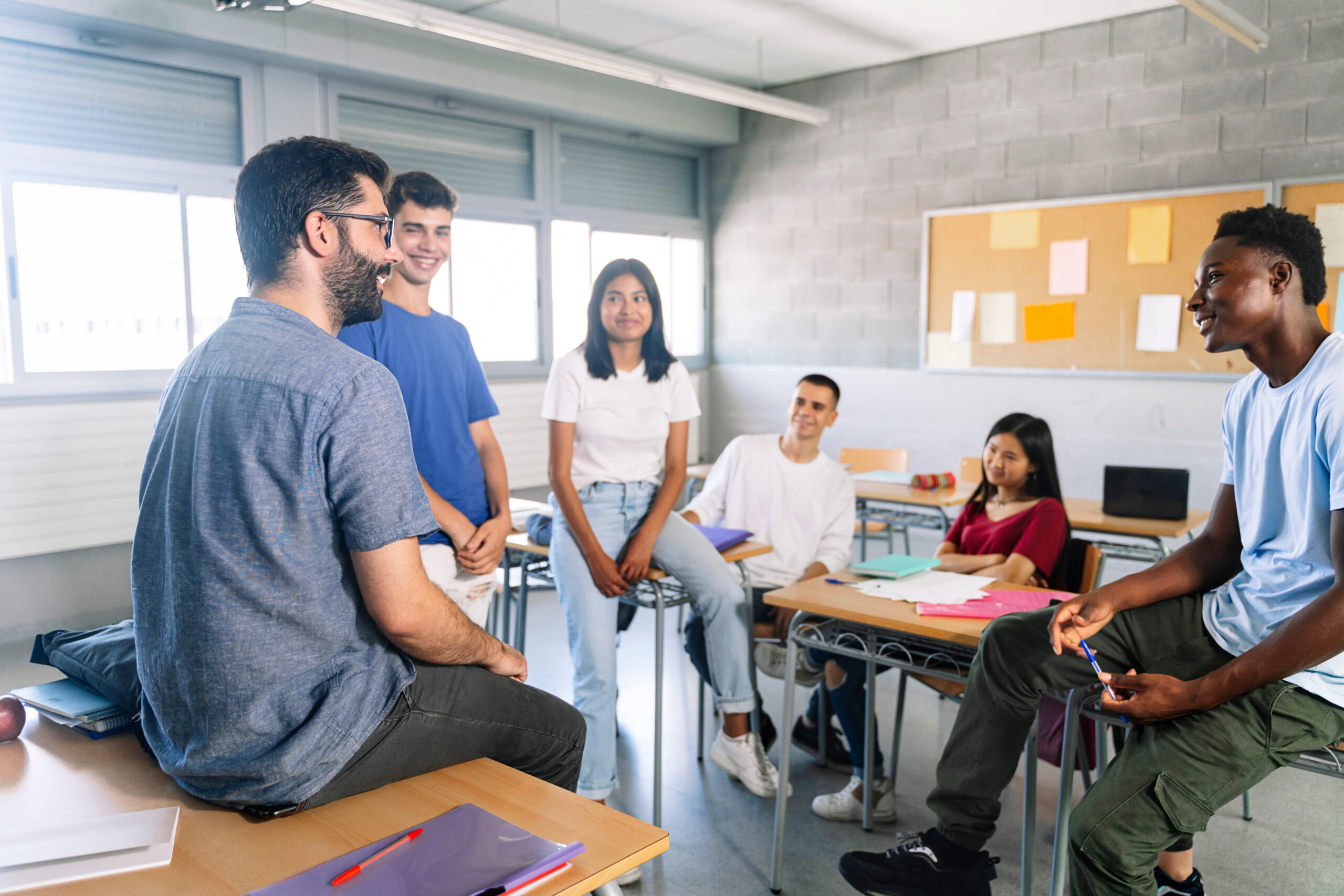 young students listening and talking with friendly young male teacher