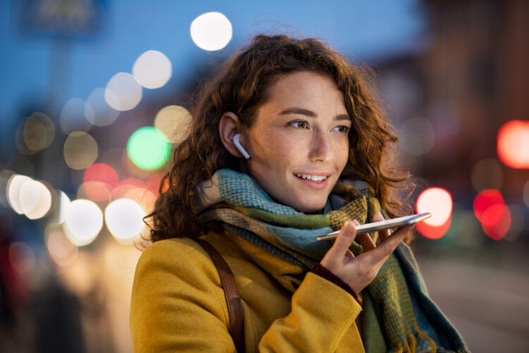 Woman sending voice note on city street in winter night
