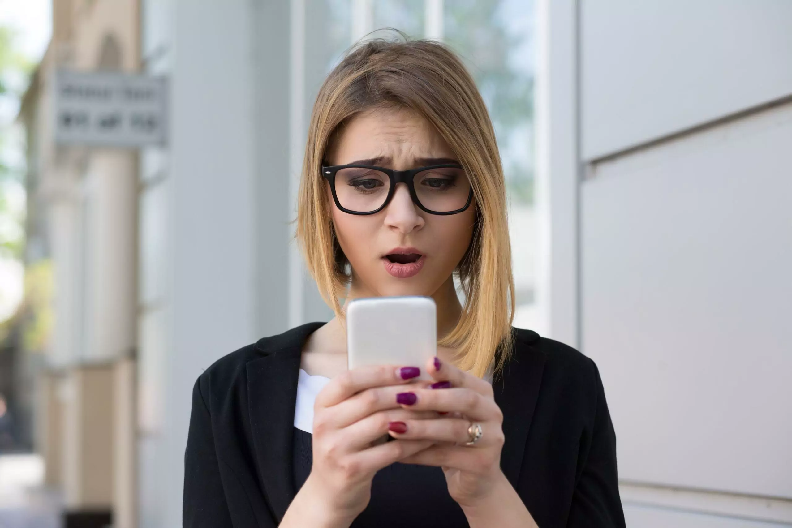 Anxious young girl looking at phone seeing bad news 