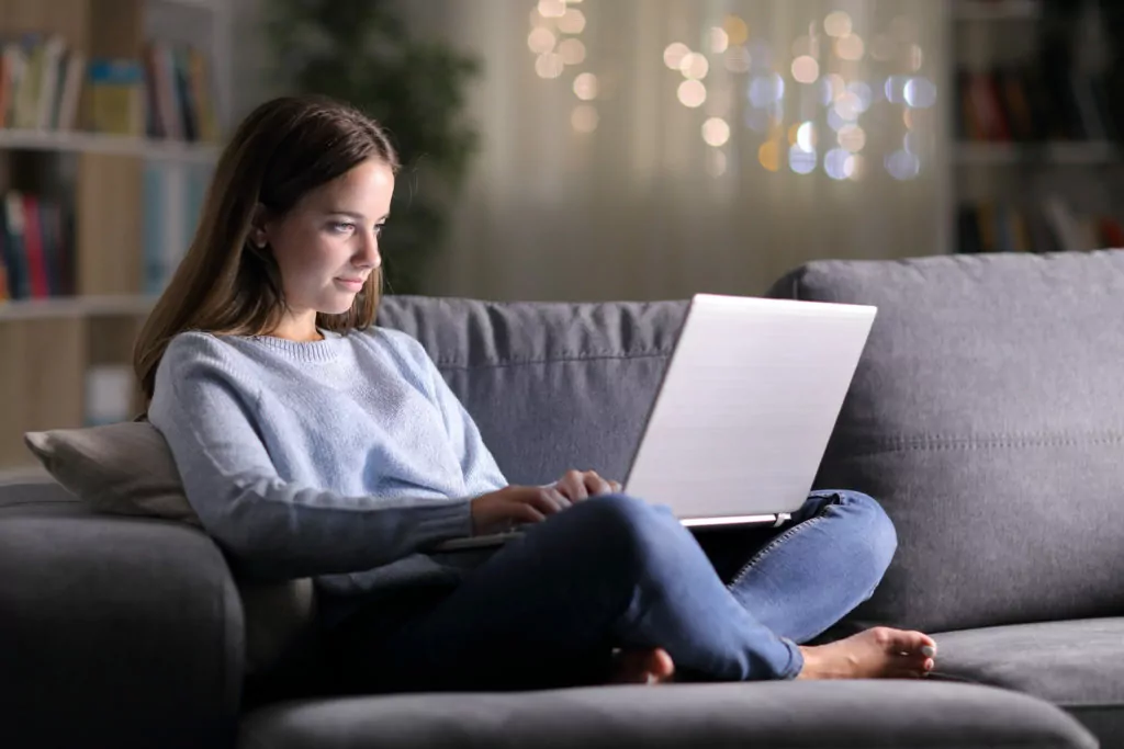 woman looking intently at the laptop screen on a sofa.