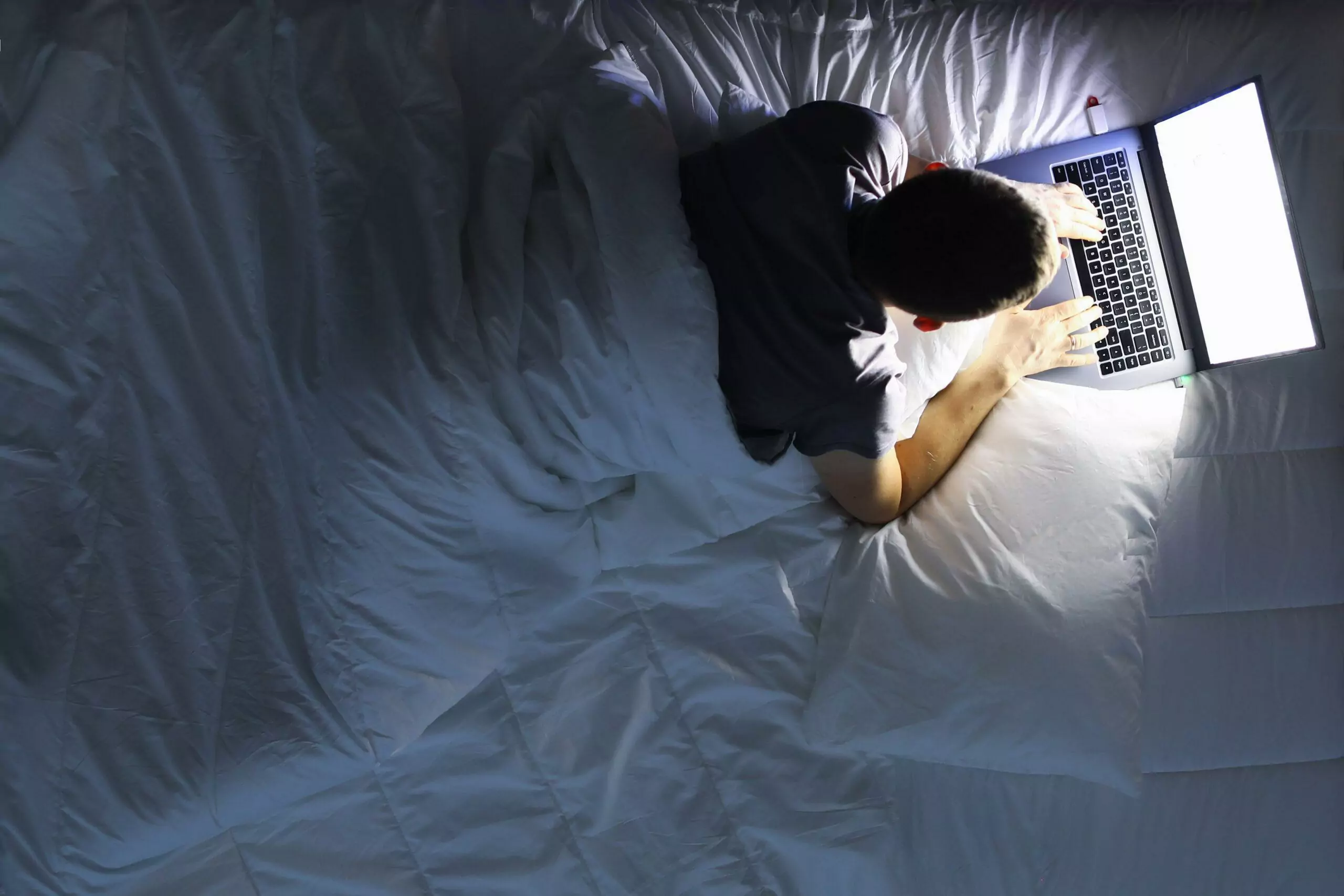 Man in bed with laptop using internet in online service love chat 