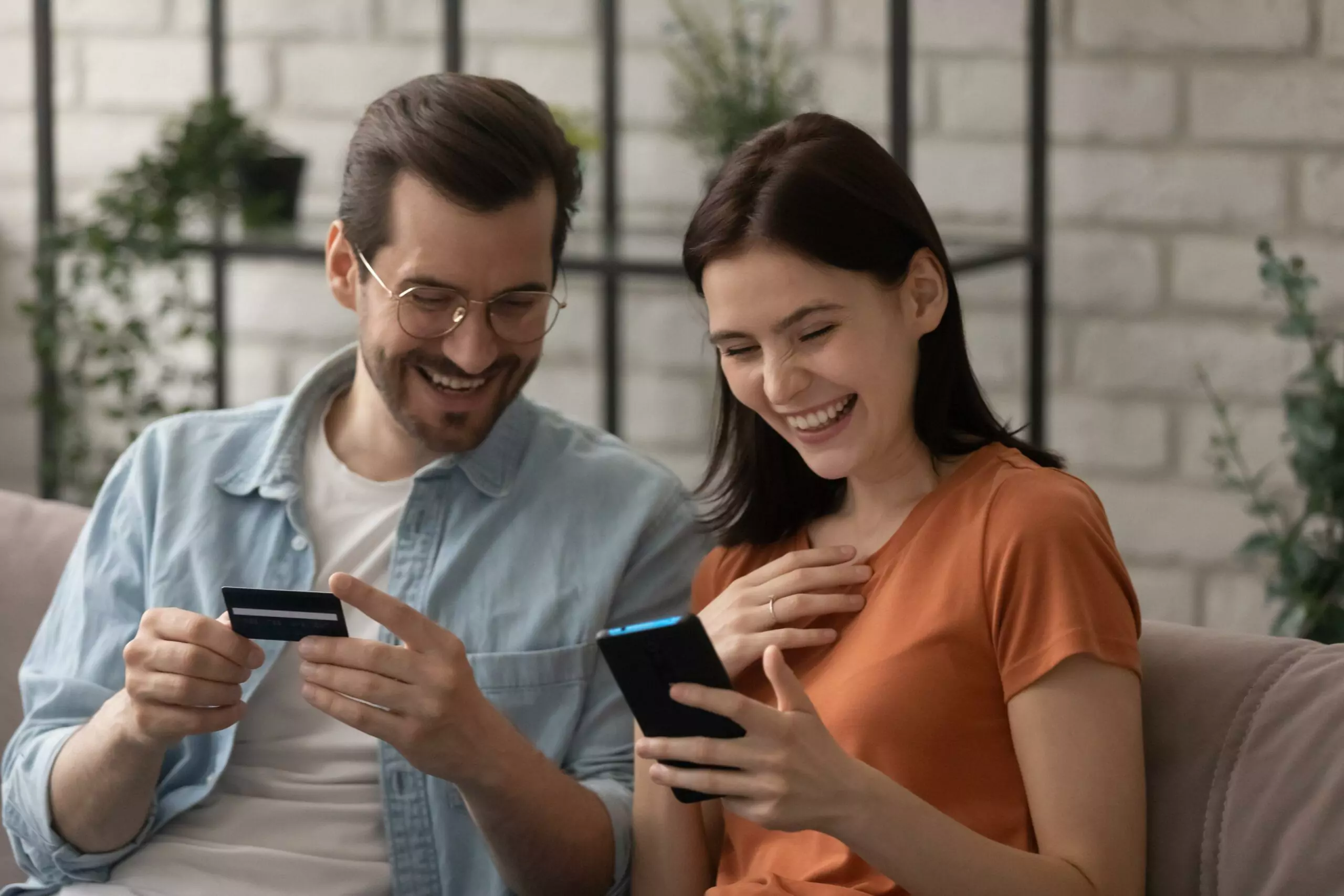 Excited millennial couple shopping online pay with credit card feel euphoric with discount or sale, smiling young man and woman clients make payment purchase on internet