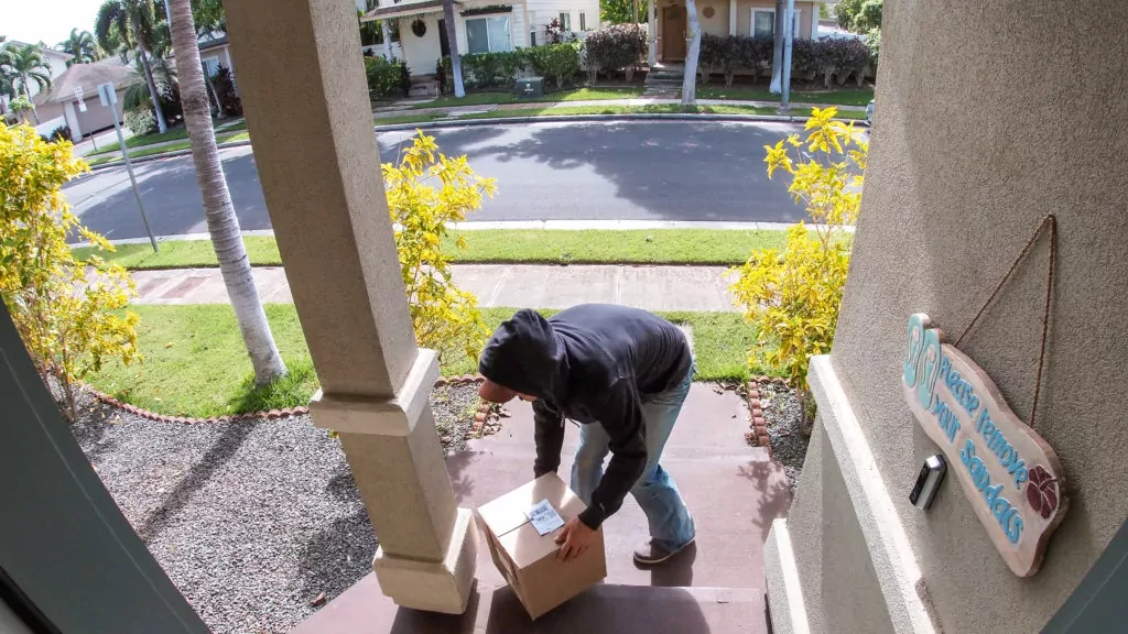 Package thief taking away parcel from the porch.