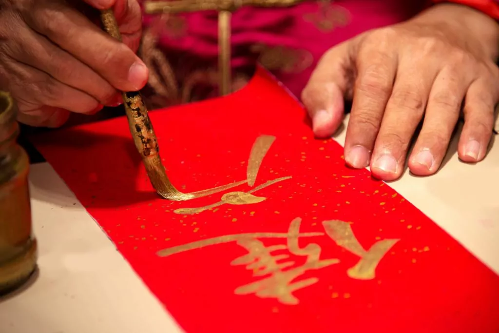 Chinese calligraphy master writing a word on red paper.