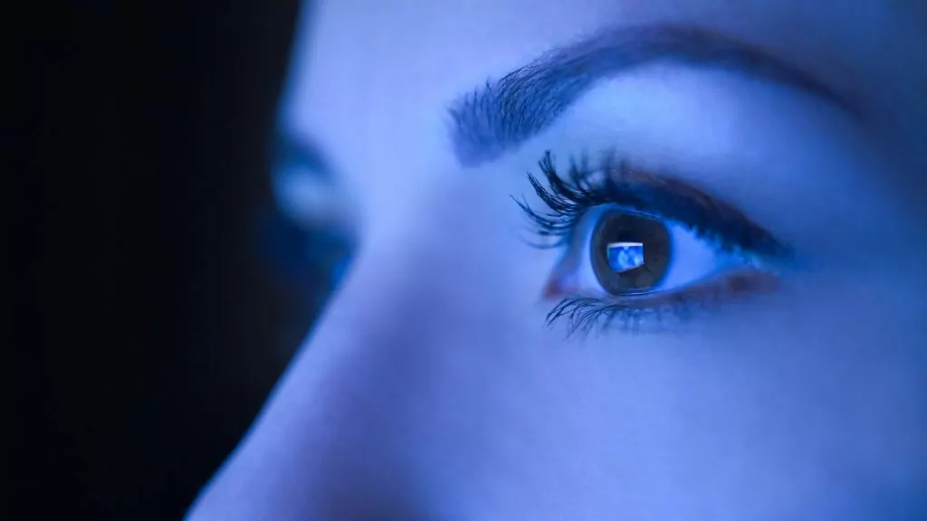 Close-up of a woman's eyes against blue light monitor.