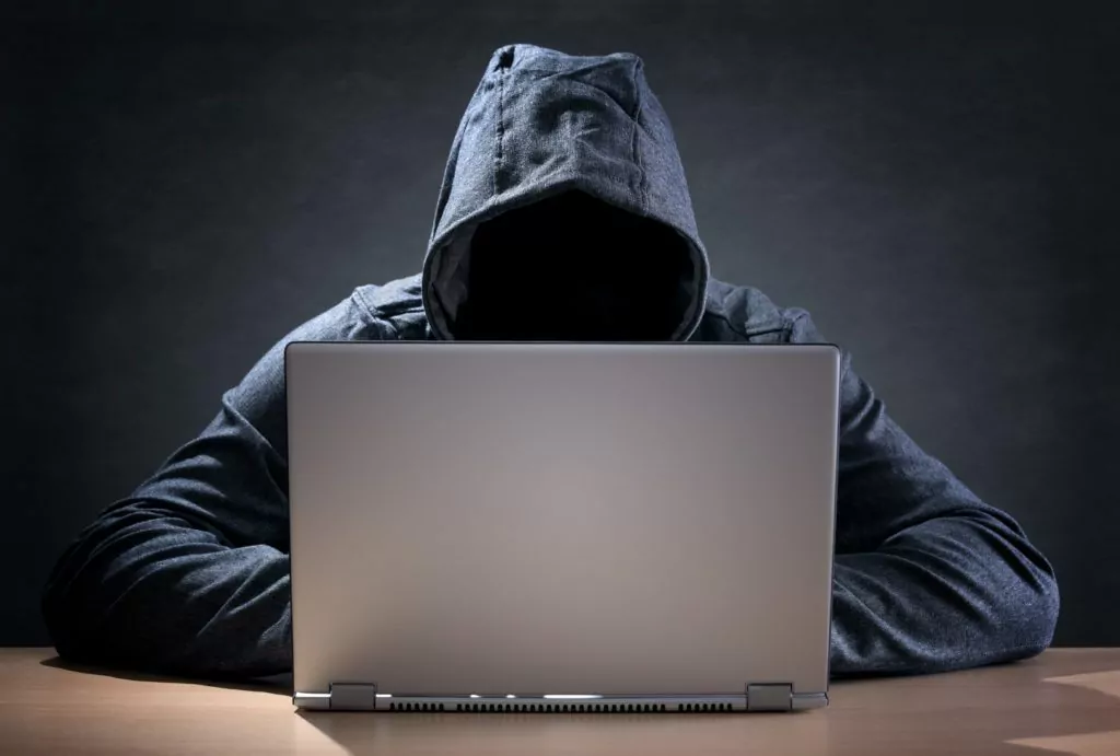 Computer hacker stealing data from a laptop.