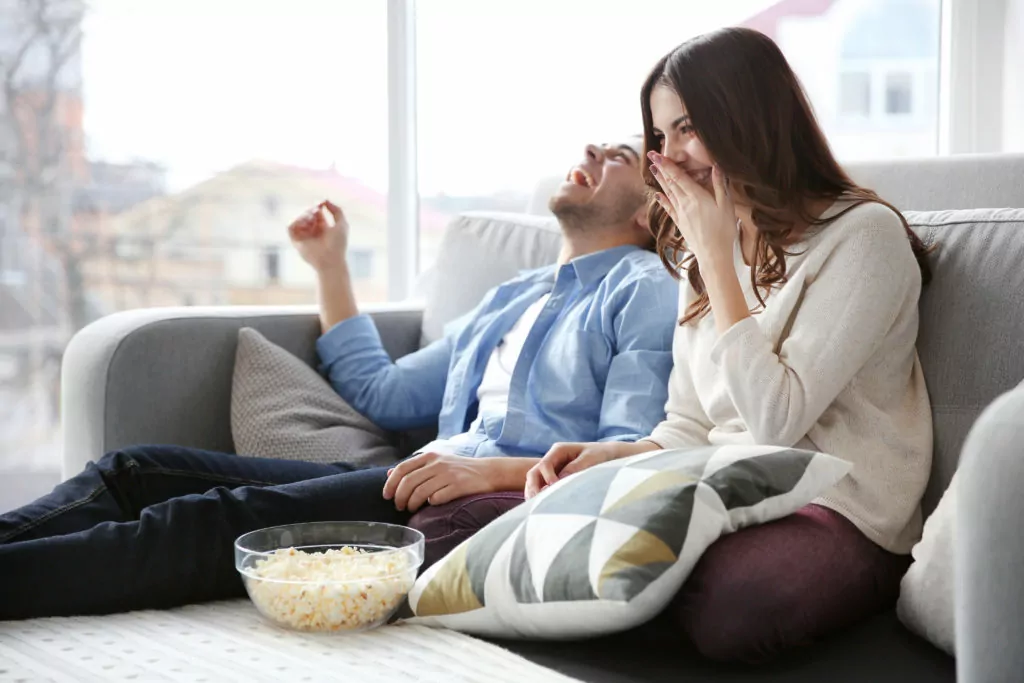 Couple watching television and having fun with popcorn.