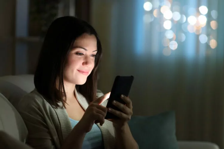 smiling woman checking social media in the night at home