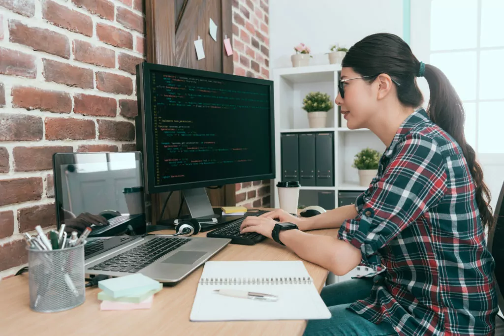 Female programmer smiling while coding on the computer.