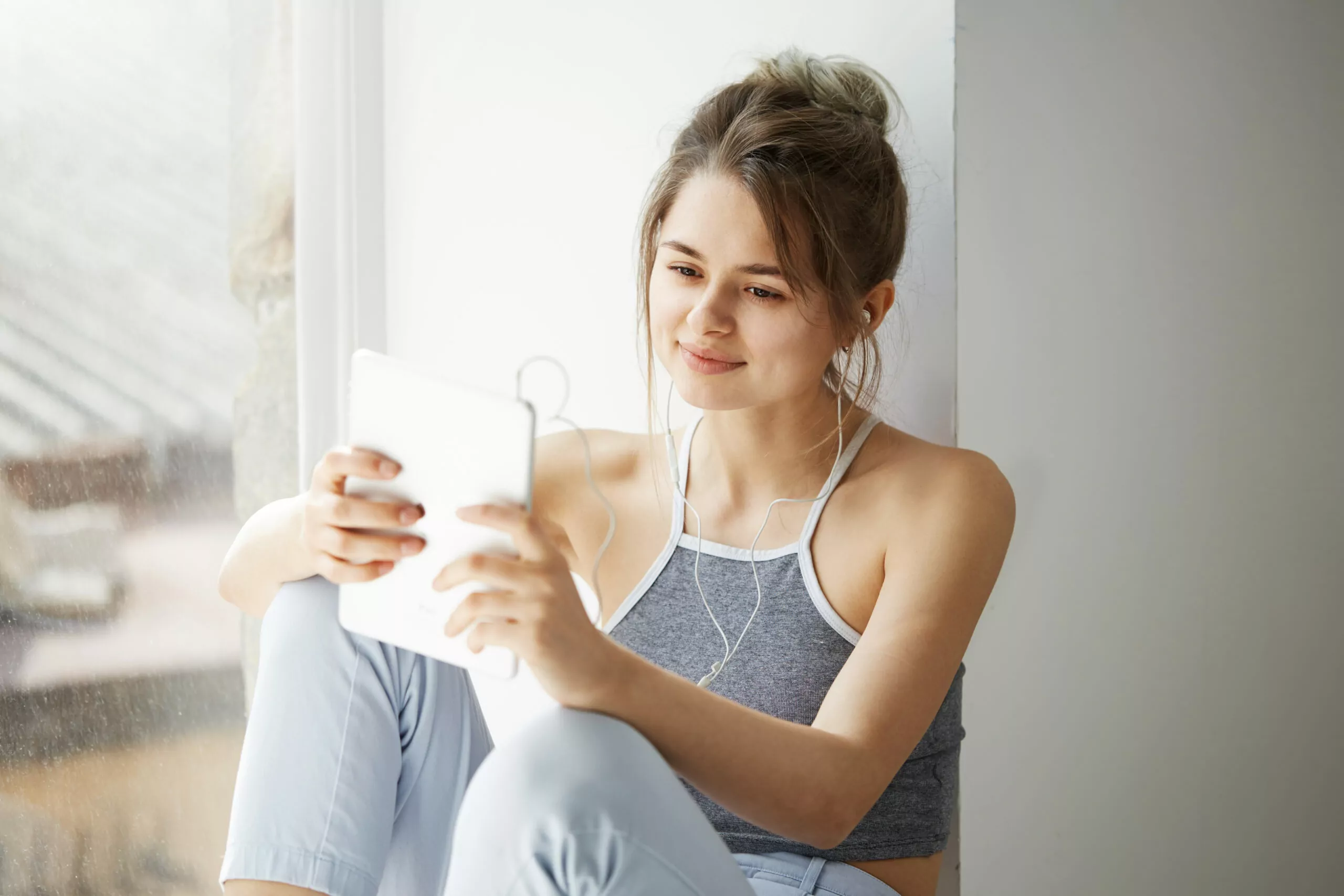 cheerful girl comfortably sitting on the floor using digital tablet device