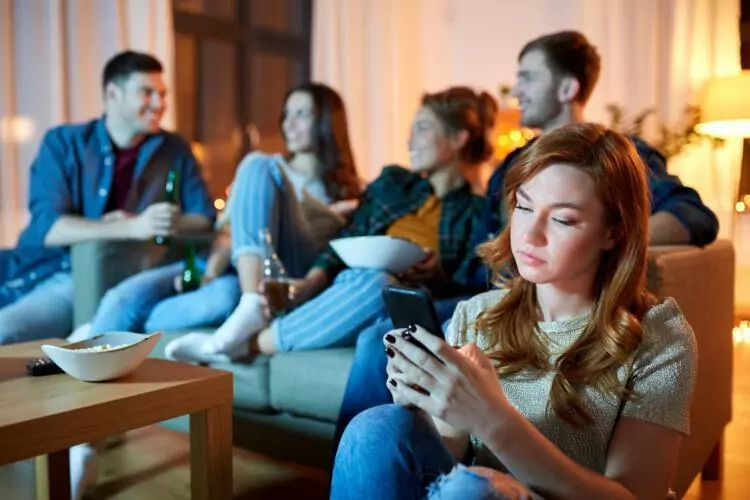 sad young woman with smartphone at home party