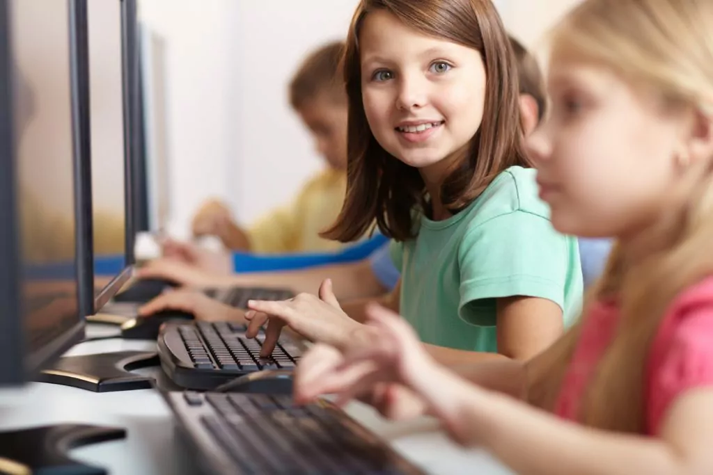 Happy schoolgirl child using a computer.
