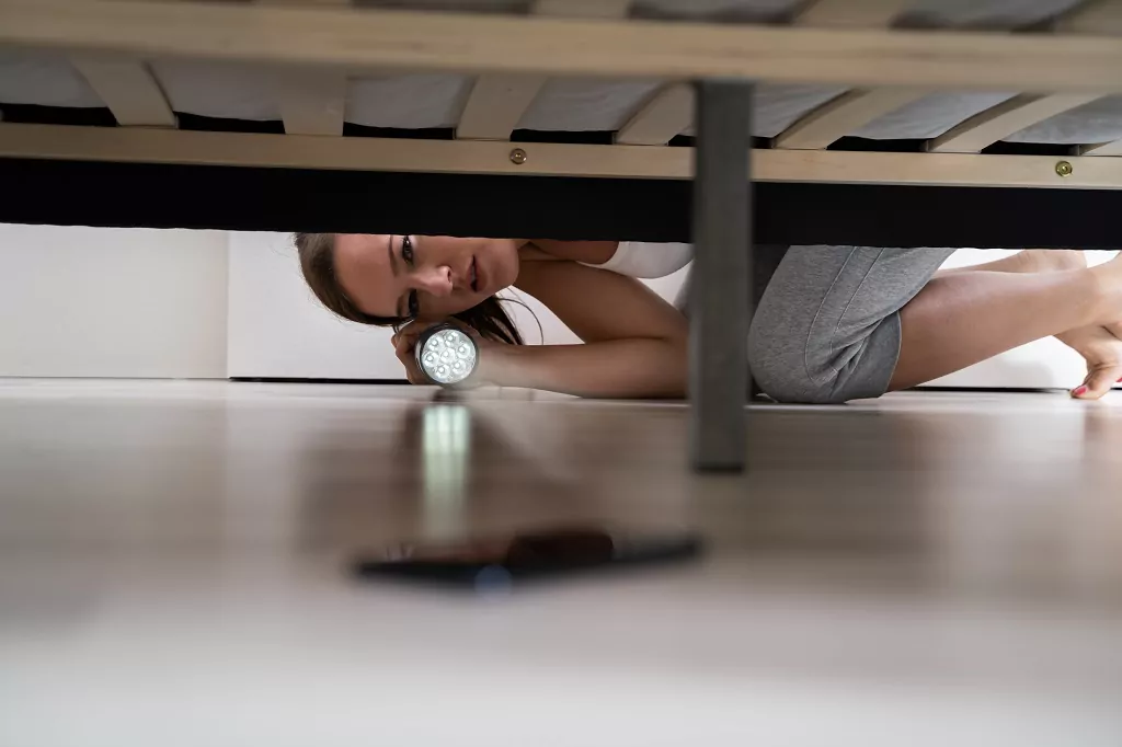 Woman finds smartphone underneath the bed.