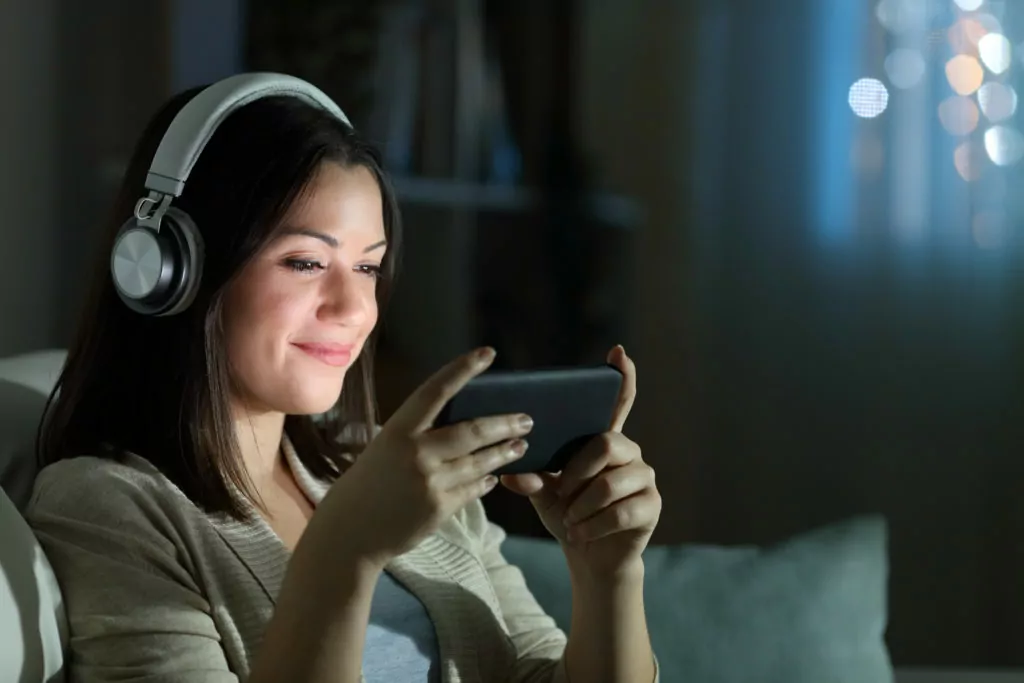 Relaxed woman watching video on mobile phone at night at home