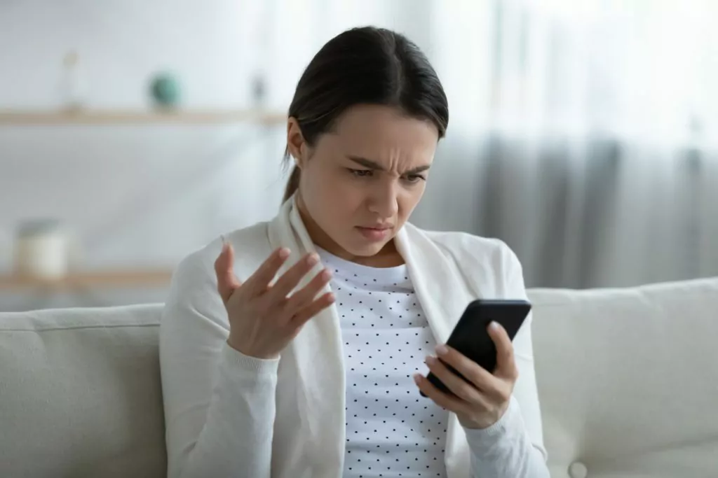 Irritated woman holding smartphone having problems with gadget feels annoyed