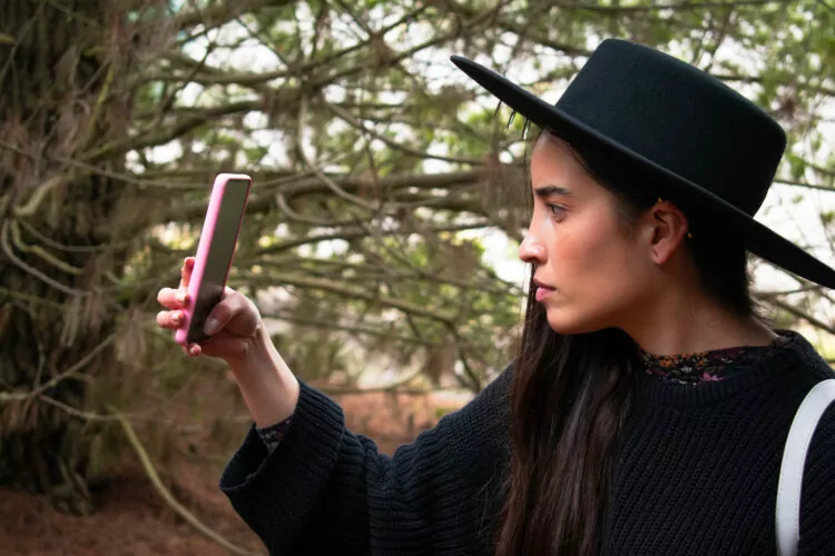 Young woman with a hat concerned looking for signal with her smartphone