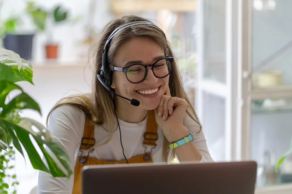 Smiling woman wearing headphones talking on a video call.